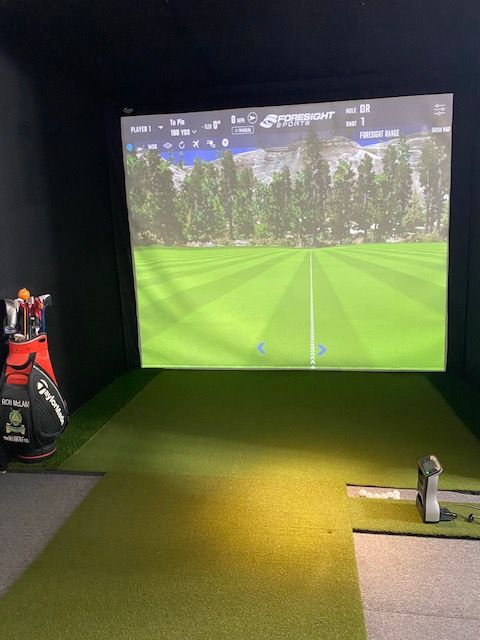 Indoor golf simulator bay with Foresight Sports screen, hitting mat and GCQuad launch monitor