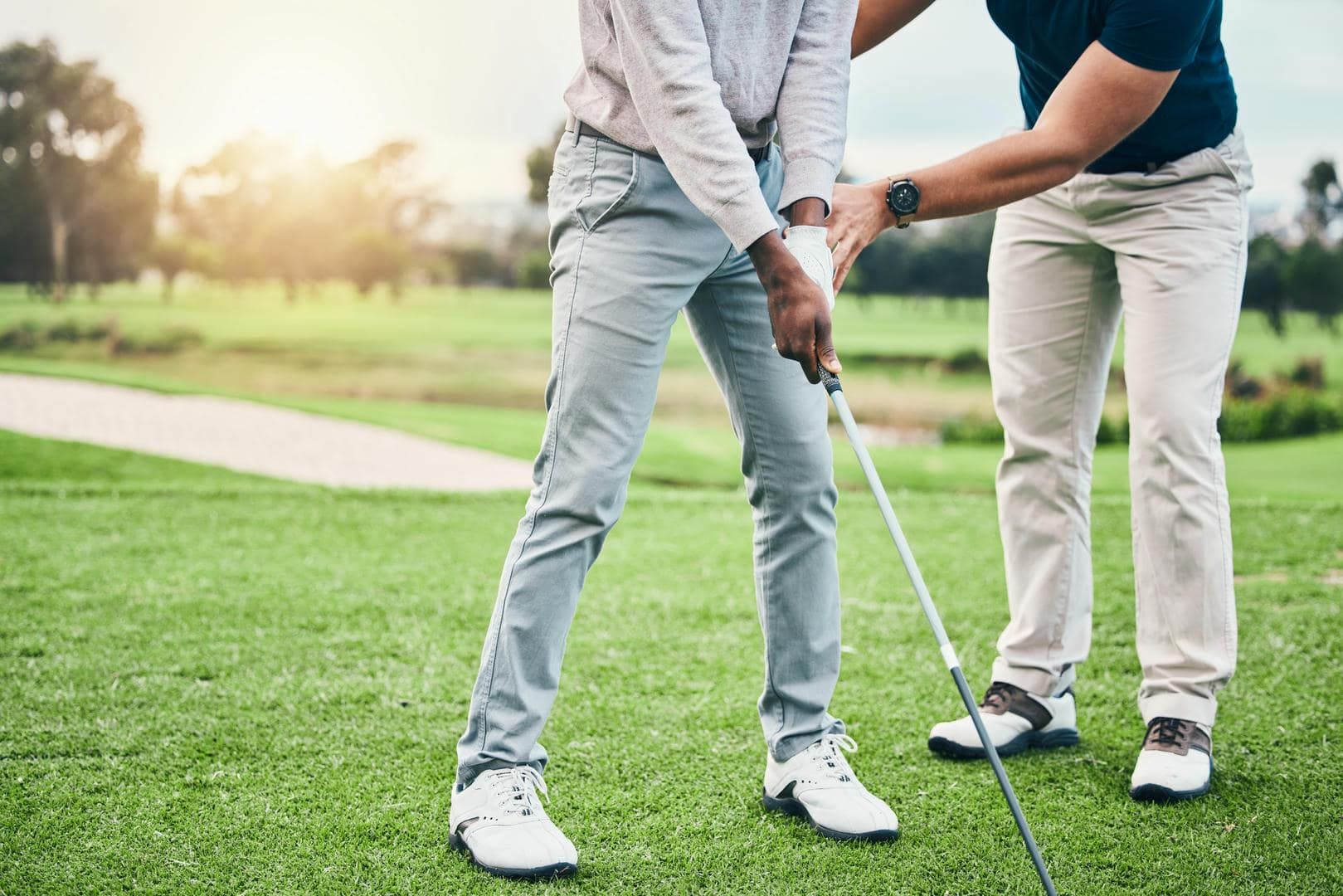 Coach guiding an adult student's grip and setup on the course